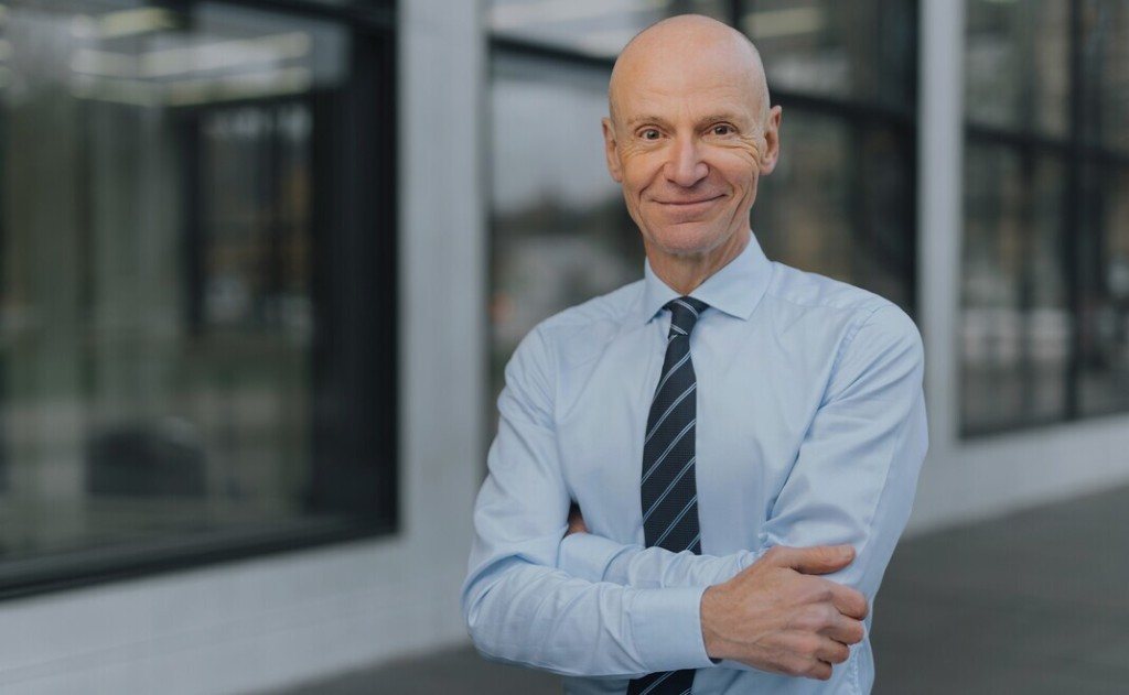 Dr. Gerd Kommer, stehend vor einem Gebäude.